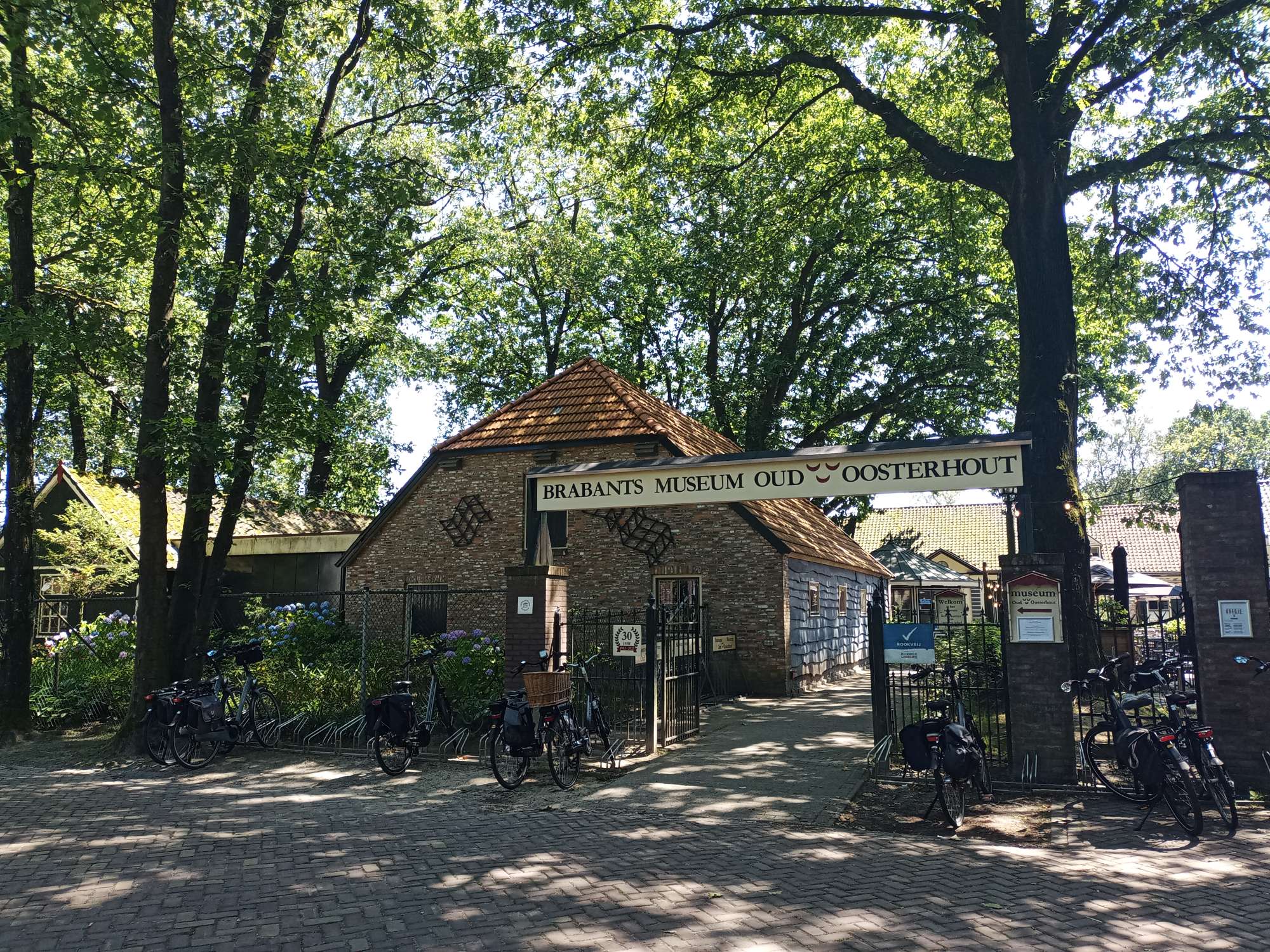 Er is een entree met een bord met daarop museum Oud-Oosterhout, links daarvan is een boerderij.