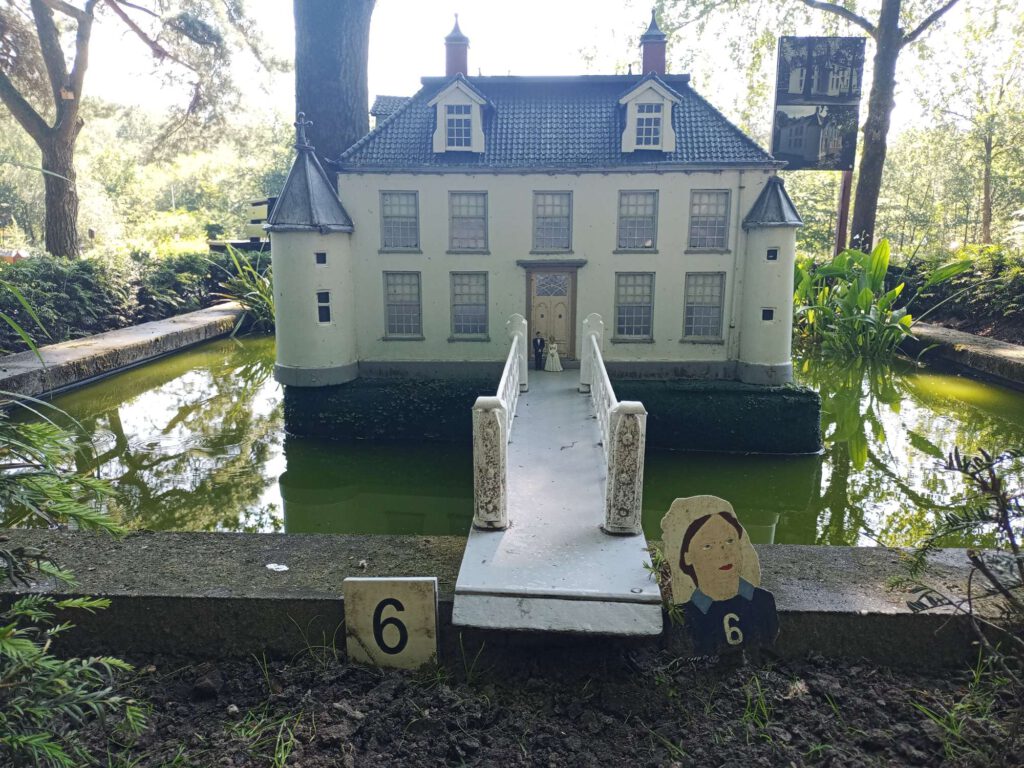 Het stadshuis is wit met een zwart dak. Om het stadshuis is een gracht en een loopbrug over de gracht naar het stadshuis. Voor het stadshuis staat een miniatuur echtpaar.