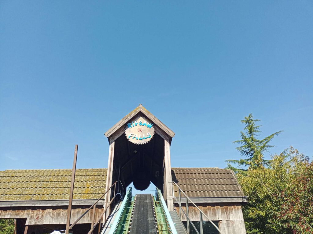 Aan de onderkant van de liftheuvel van Ripsaw Falls, waarbij je de zwarte lopende band omhoog ziet, terwijl het omhult is in een houten huisje waar de baan door loopt en onderaan het station is van de baan.