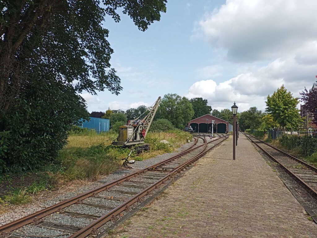 Vanaf dit punt kijk je naar de remise van station Boekelo, waar in het midden een perron is. Links lopen de sporen naar de remise en links staat ook een hijskraan.