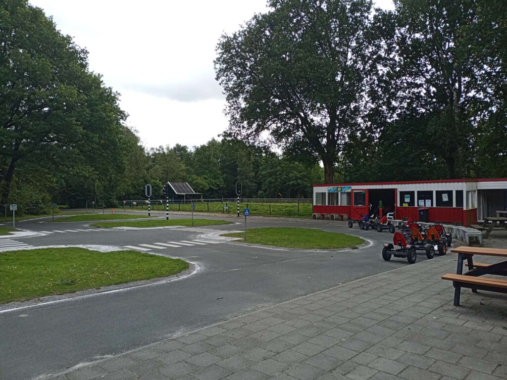 Rechts staan picknickbanken voor wachtende ouders, daar staan ook de skelters ogesteld. De verkeerstuin is gemaakt van asfalt en hier staan borden en een stoplichtinstallatie. De perkjes buiten de wegen zijn met gras ingezaaid.