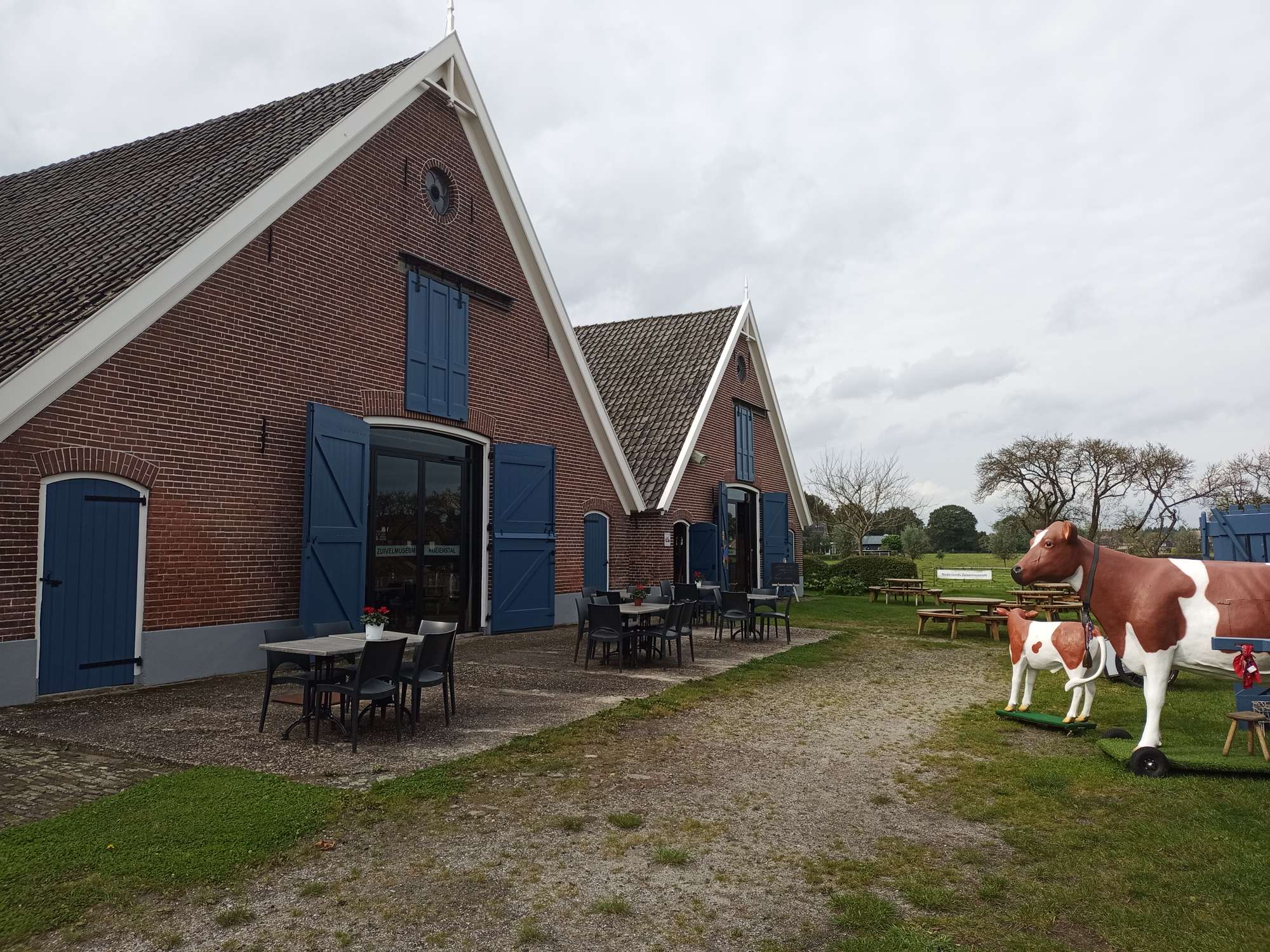 Het voorterrein van het museum, links zijn de stallen te zien, rechts een model van een koe.